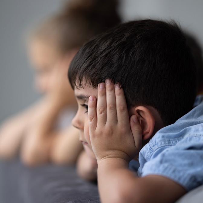 A young boy with his hands against his head