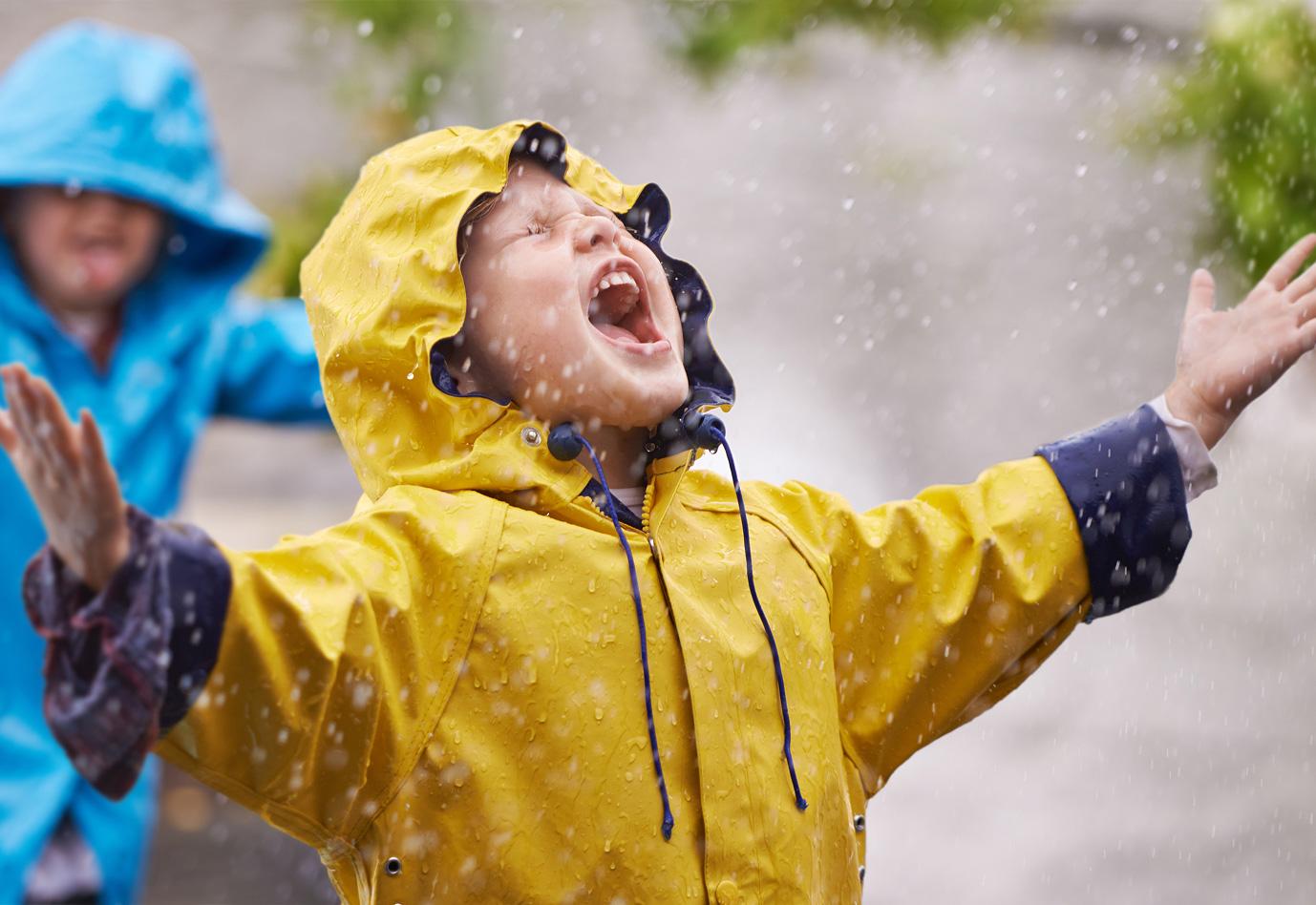 A happy boy playing in the rain